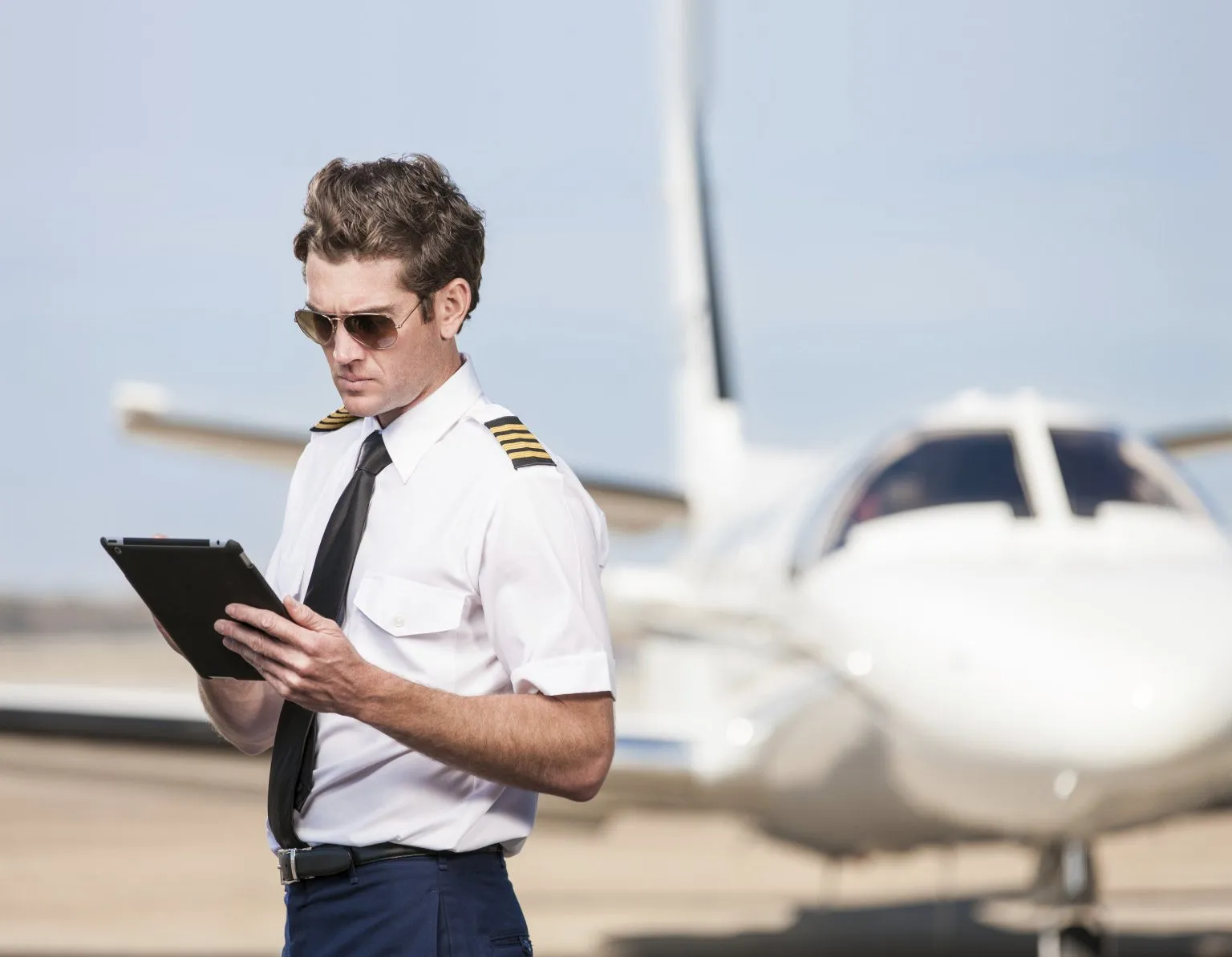 Piloto de COLJET revisando su iPad frente a un jet